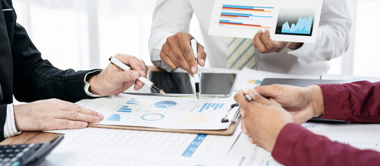 Three people are sitting at a table with a whiteboard and a few papers