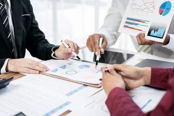 Three people are sitting at a table with papers and graphs in front of them