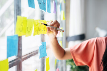 A woman is writing on a wall with sticky notes