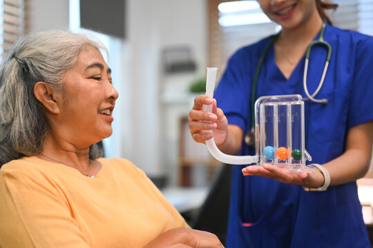 Physical therapist assisting mature woman with using a spirometer to improve the functioning of lungs