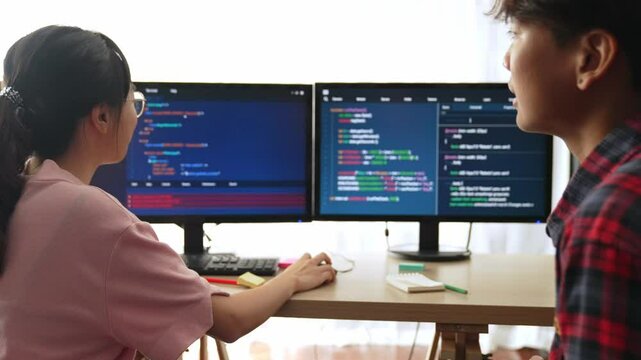 Slow motion back end software developer engineer for computer programming working together on debugging writing computing code, solving complex algorithms display on monitor in office. Burgeoning