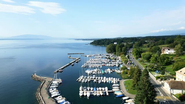 Push in drone shot above Port of Nyon with Geneva in the back and the Geneva Lake in Switzerland.