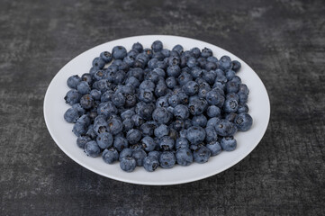 Izolowany biały talerz pełny świeżych czarnych jagod