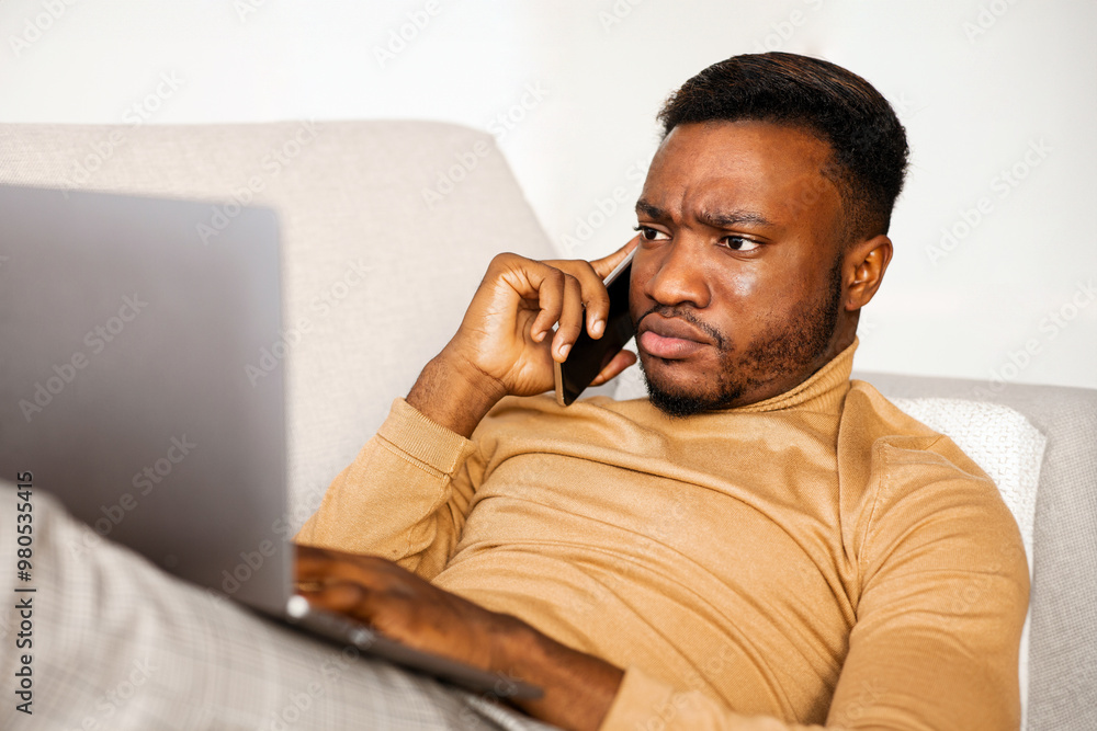 Aufkleber Computer Problem. Discontended Afro Guy Talking On Phone Frowning And Using Laptop Lying On Sofa At Home. Selective Focus
