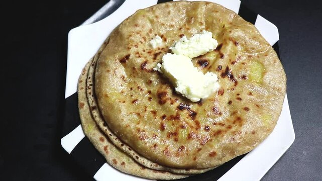 Aloo Paratha made with whole wheat flour, boiled potatoes, and spices  served with white Butter.