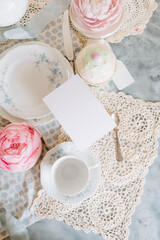 Mockup card,  teacup and saucer are on a table with a plate, tea time