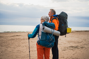 Hiking tourism adventure. Senior couple man woman enjoying outdoor recreation hiking on beach. Happy old people backpackers hikers enjoy walking hike trekking tourism active vacation beauty of nature