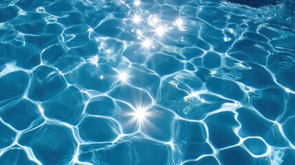 Bright blue swimming pool with shimmering water. The sunlight reflects on the rippled surface, creating a beautiful pattern of light and shadow on the clear water