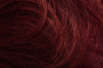 Dark red hair close-up as a background. Women's long brown hair. Beautifully styled wavy shiny...