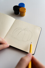 Starting a pumpkin sketch in a notebook with gouache