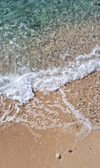 A detailed view of a sandy beach and a breaking wave