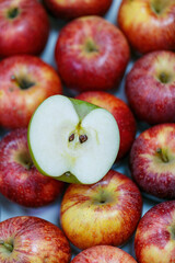 Mobile vertical wallpaper photograph of many red apples with cut apple green apple revealing the seeds in the center. The contrast between the single green apple and the surrounding red apples.