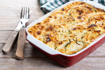 Casserole with cheese and gratin zucchini on wooden table