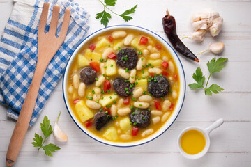 Bean stew with black pudding, peppers and potatoes. Top view table with decoration.