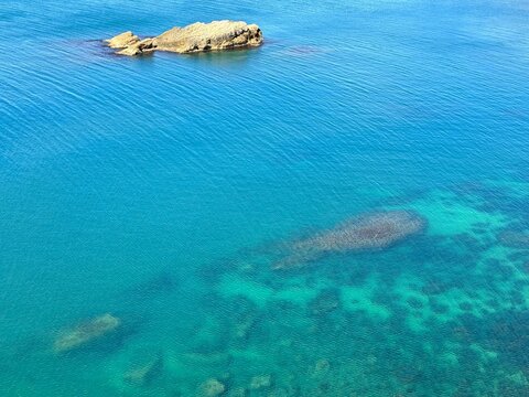 Azure blue clear sea waters and rock aerial view. 