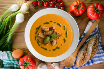 Tomato soup with basil oil and croutons. Top view table with  decoration.