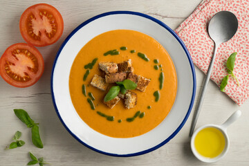 Tomato soup with basil oil and croutons. Top view table with  decoration.