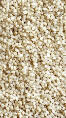 Natural light highlights the fine texture of white sesame seeds on a wooden surface