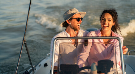 A happy couple enjoying a boat ride on a sunny day, with the man wearing a hat and sunglasses and...