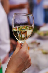 A woman's hand with a glass of white wine at the banquet table. traditions of drinking alcohol and making toasts on holidays.