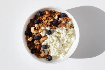 Top View of Bowl of Cottage Cheese with Cashew Nuts, Almonds, Seeds Granola, and Blueberries. Healthy Breakfast Food.