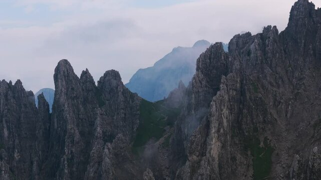 Lombardy, Italy - A Captivating Scene of Fog-Draped, Jagged Peaks Rising From the Rugged Slopes of Grignetta - Pan Up Shot