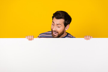 Photo of young crazy adult bearded man holding billboard empty blank space information isolated on yellow color background