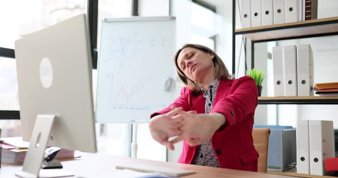 Young female IT business employee raise hand doing stretching relax. Manager break leaning body sit work at office desk with laptop computer