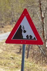Warning road sign. A red triangle sign indicating falling rocks on a white background.