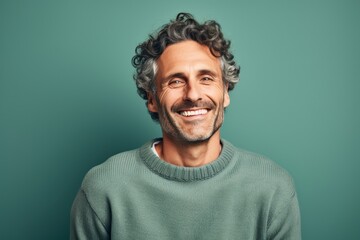 Fototapeta premium Portrait of a smiling man in his 40s dressed in a warm wool sweater isolated on pastel teal background