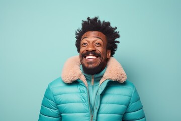 Obraz premium Portrait of a joyful afro-american man in his 40s sporting a quilted insulated jacket isolated in pastel teal background