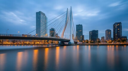 A modern bridge illuminated at dusk, reflecting in calm waters amidst city skyscrapers.