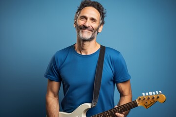 Portrait of a glad man in his 40s sporting a vintage band t-shirt over soft blue background