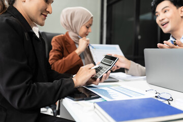 Business team using a calculator to calculate the numbers of statistic business profits growth rate on documents graph data, desk in the office.