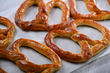 Freshly baked, golden-brown pretzels laid out on parchment paper, glistening with a slight sheen of butter. These crispy yet soft pretzels are perfect for snacking