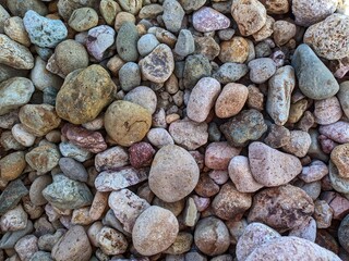 Background of smooth round pebble texture. Close up gravel of various colors and patterns, gray gravel, beige gravel, reddish pebbles. Natural pebbles, texture of pebbles. Gravel texture. 