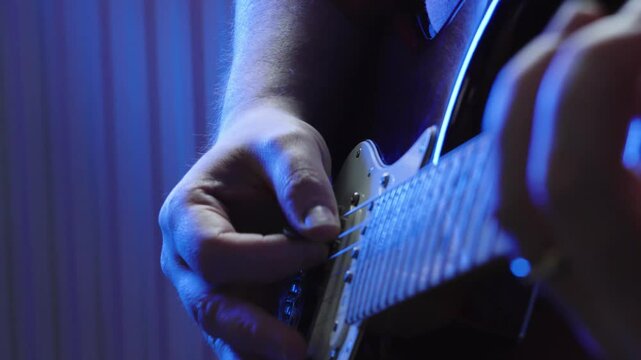 Blue Concert Lighting with Guitarist Playing Electric Red Stratocaster Guitar with Shallow Depth of Field in Slow Motion Close Up 4K