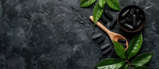 Tablets of activated charcoal a wooden spoon and leaves arranged beautifully in a copy space image