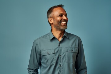 Fototapeta premium Portrait of a glad indian man in his 40s sporting a breathable hiking shirt in front of soft blue background