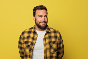 Fototapeta premium Portrait of a content man in his 30s wearing a comfy flannel shirt on soft yellow background