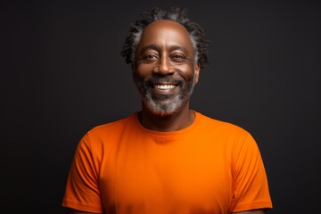 Fototapeta premium Portrait of a smiling afro-american man in his 50s showing off a lightweight base layer in soft orange background