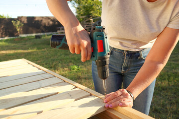 Female carpenter at work using hand drilling machine. Woman using an drilling tool on wood in a...