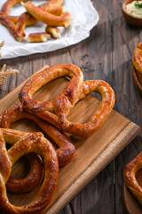 A fresh batch of golden-brown pretzels rests on a wooden cutting board, ready to be served. The warm, crispy texture and simple presentation create a perfect snack-time treat, perfect for sharing