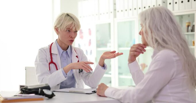 Doctor cardiologist communicates with elderly patient in clinic. Medical care for elderly
