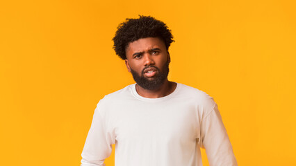 Indignant young african american man over orange studio background, copy space