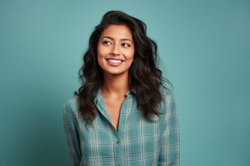 Obraz premium Portrait of a glad indian woman in her 20s wearing a comfy flannel shirt isolated on soft teal background