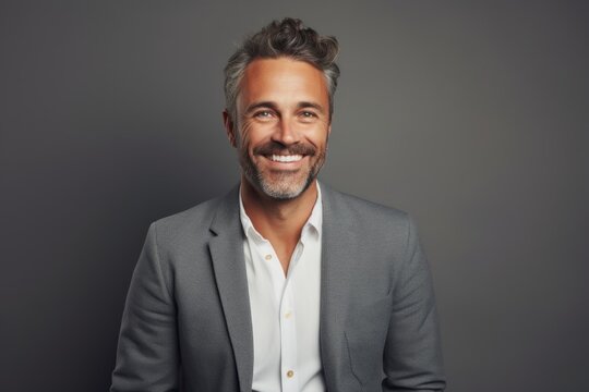 Portrait of a smiling man in his 40s dressed in a stylish blazer in front of soft gray background