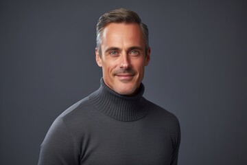 Fototapeta premium Portrait of a tender man in his 40s wearing a classic turtleneck sweater isolated on soft gray background