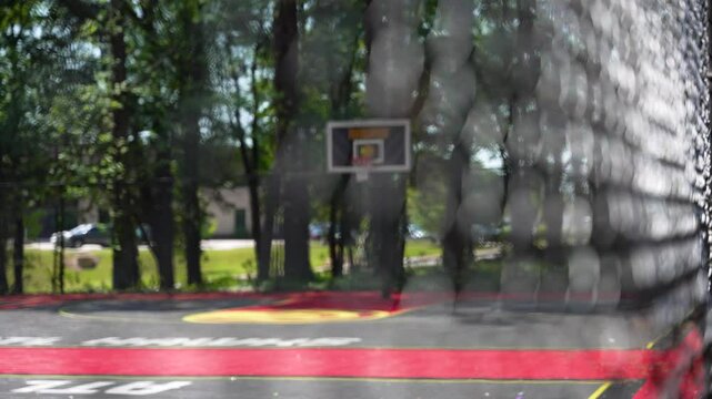 Wide shot, racking focus of Atlanta Hawks basketball backboard as seen through a chain link fence