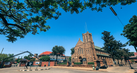 Historic stone church in Bulawayo surrounded by greenery and clear skies during the day